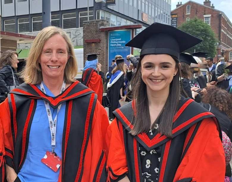 Two ladies in black and red academic gowns