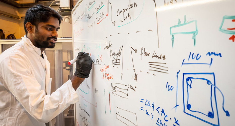 Engineering student writing equations on white board
