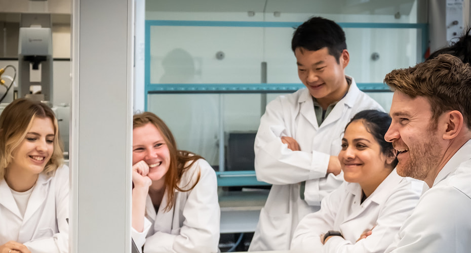 Group of engineering staff and students laughing in workshop