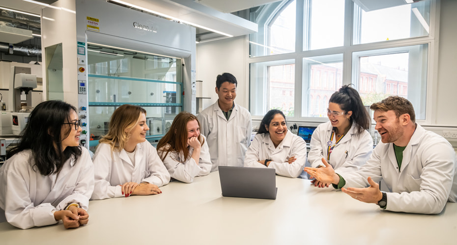 Group of engineering staff and students laughing in workshop