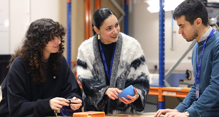 Product Design engineering student and tutors looking at plastic objects in workshop