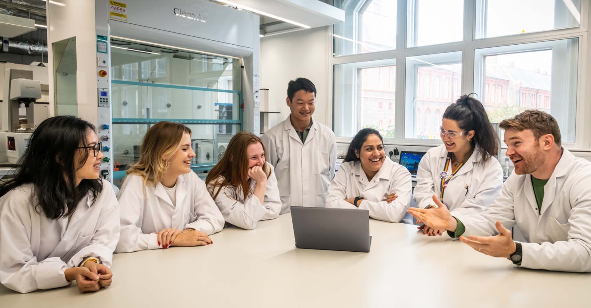 Engineering research group sat around table with laptop in lab