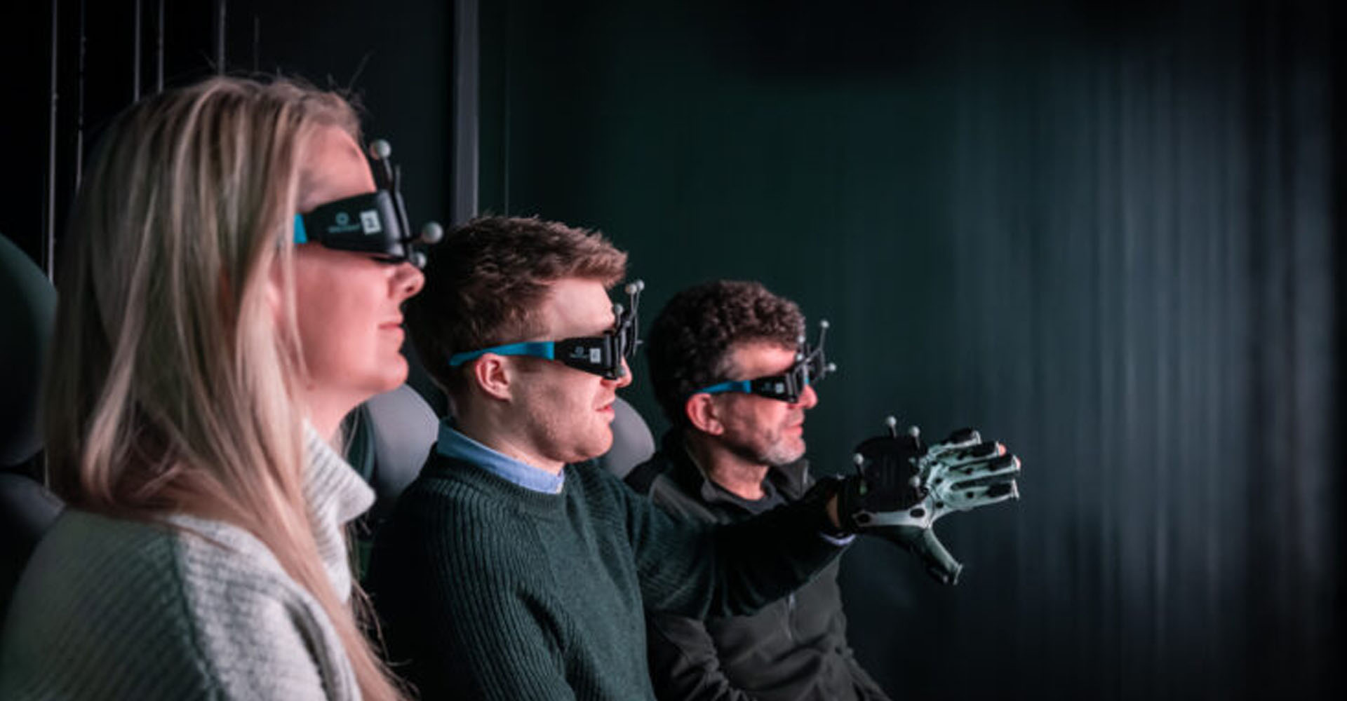 Three people using virtual reality headsets and glove