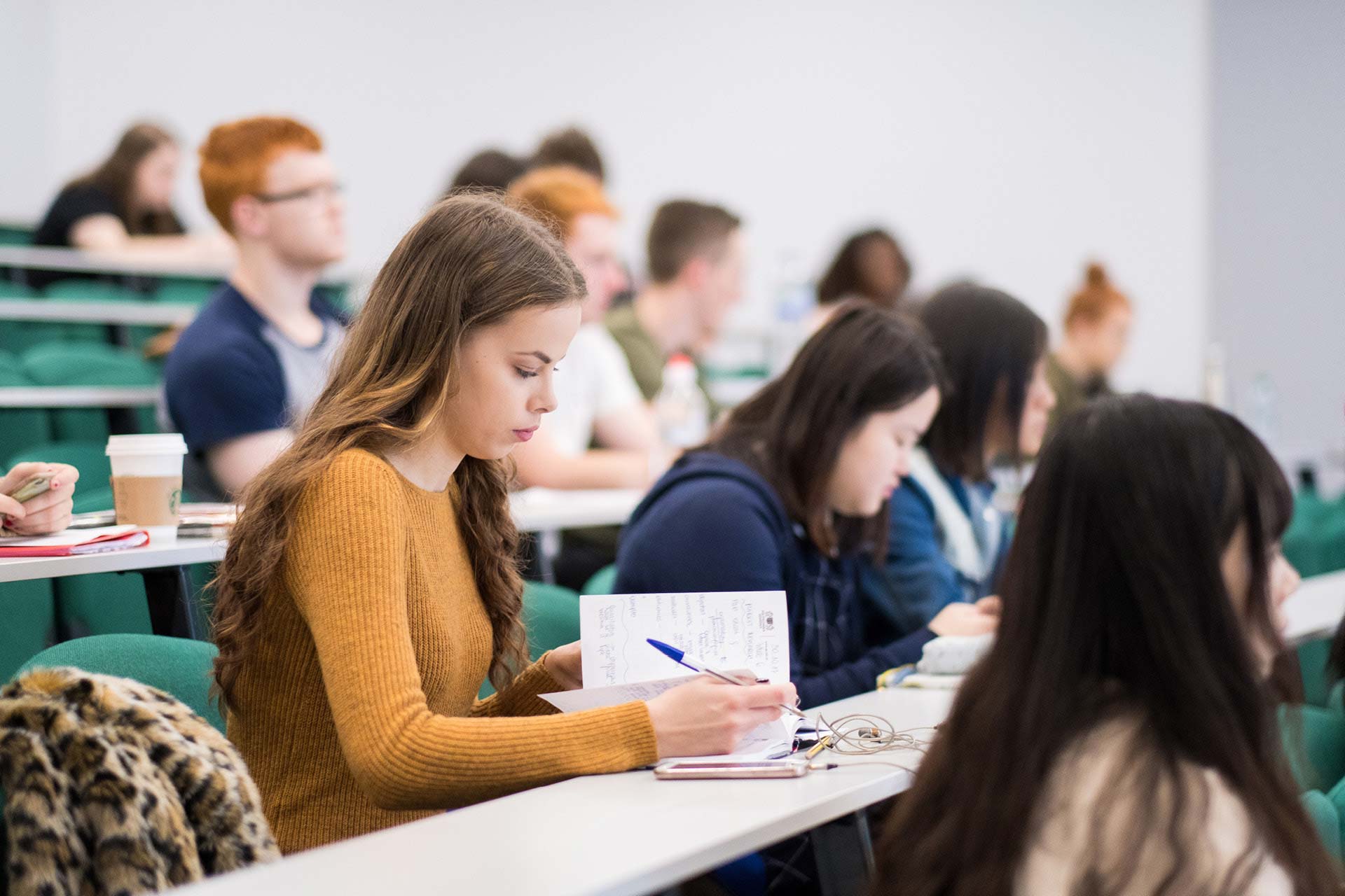 Management School student making notes in lecture theatre