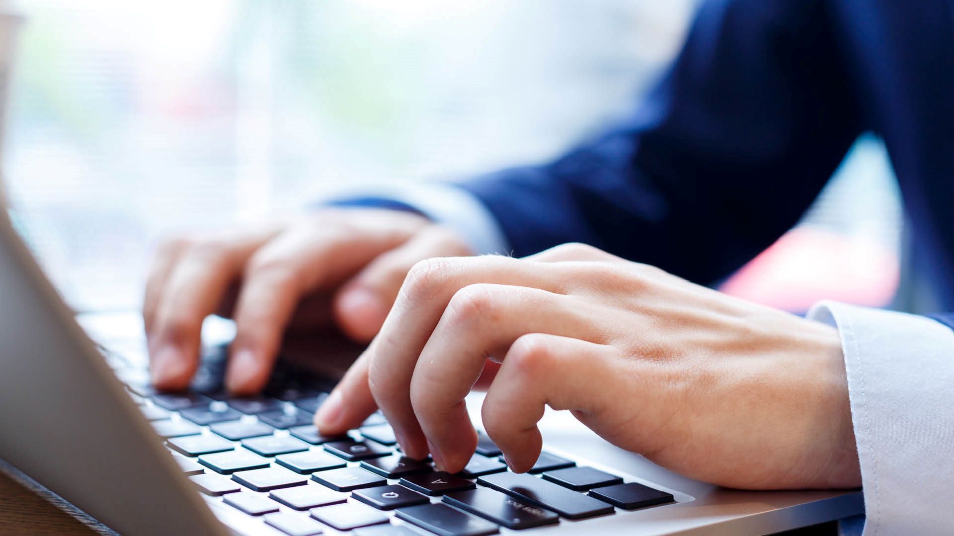 Close up of hands typing on a laptop keyboard