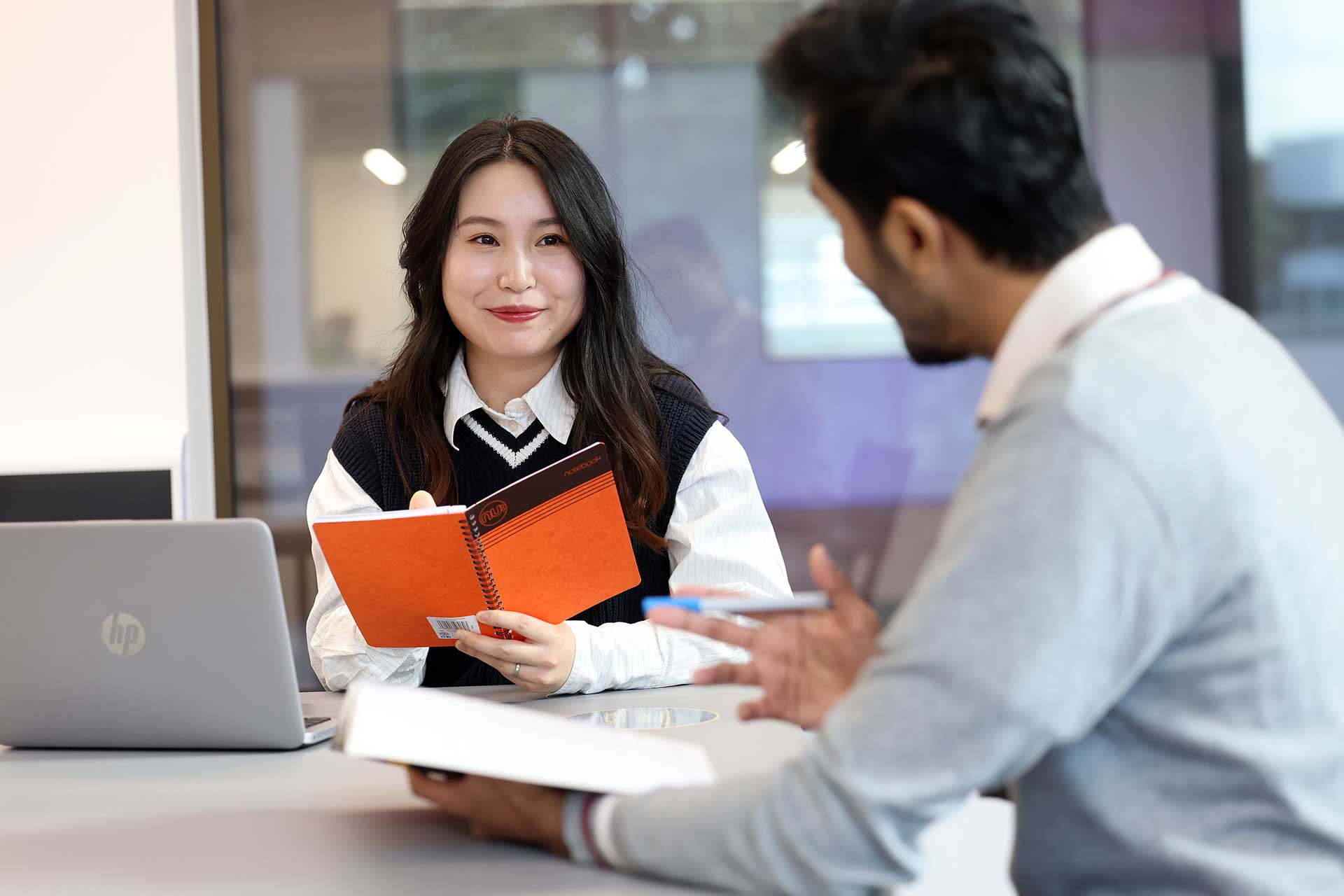 Postgraduate students working at a desk and smiling