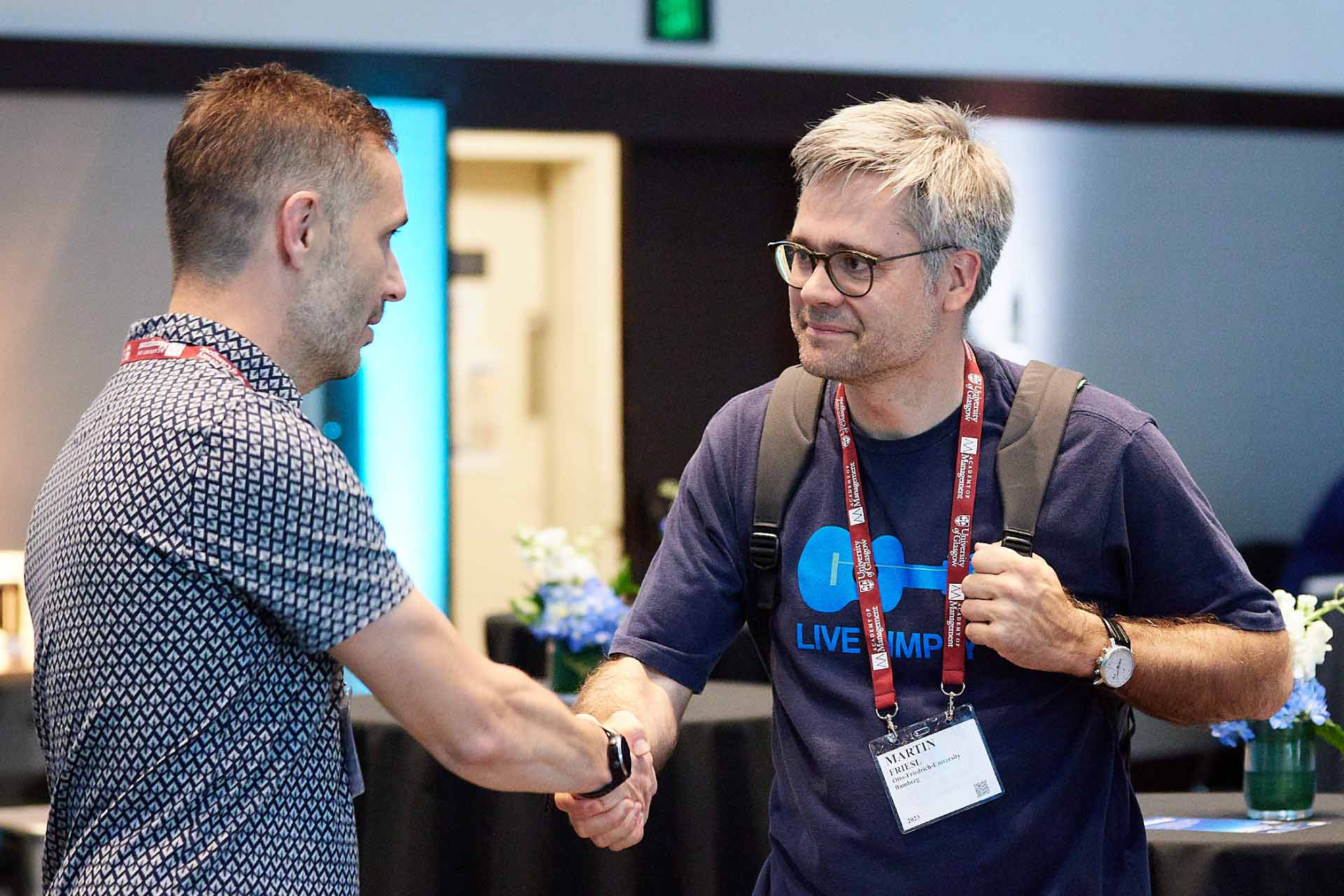Two male academics shaking hands at the AOM 23 University of Liverpool reception.