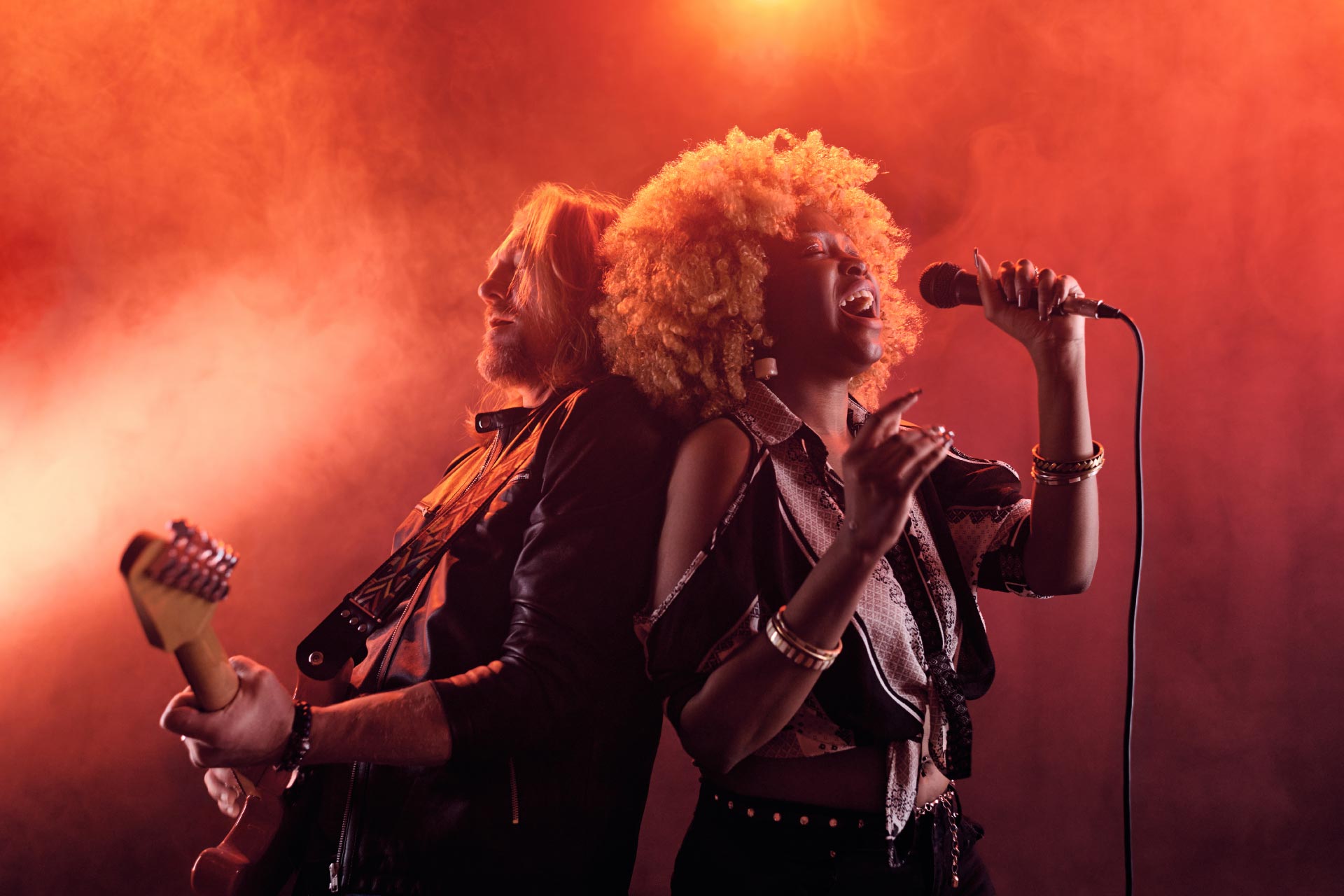 A female singer and male guitarist performing during at a live concert.