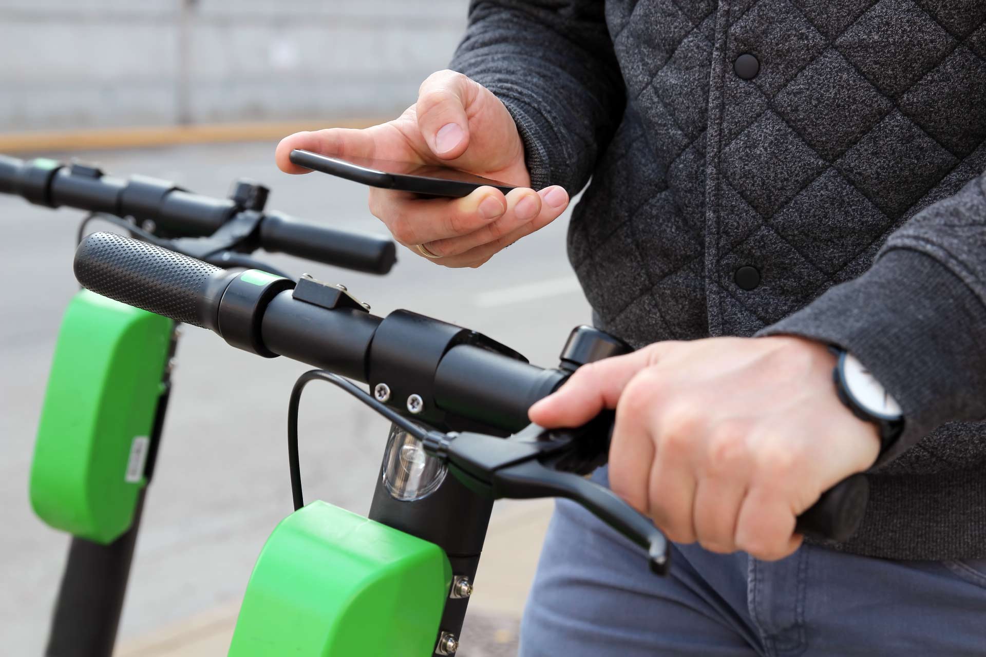 Image of male booking electric scooter on his phone