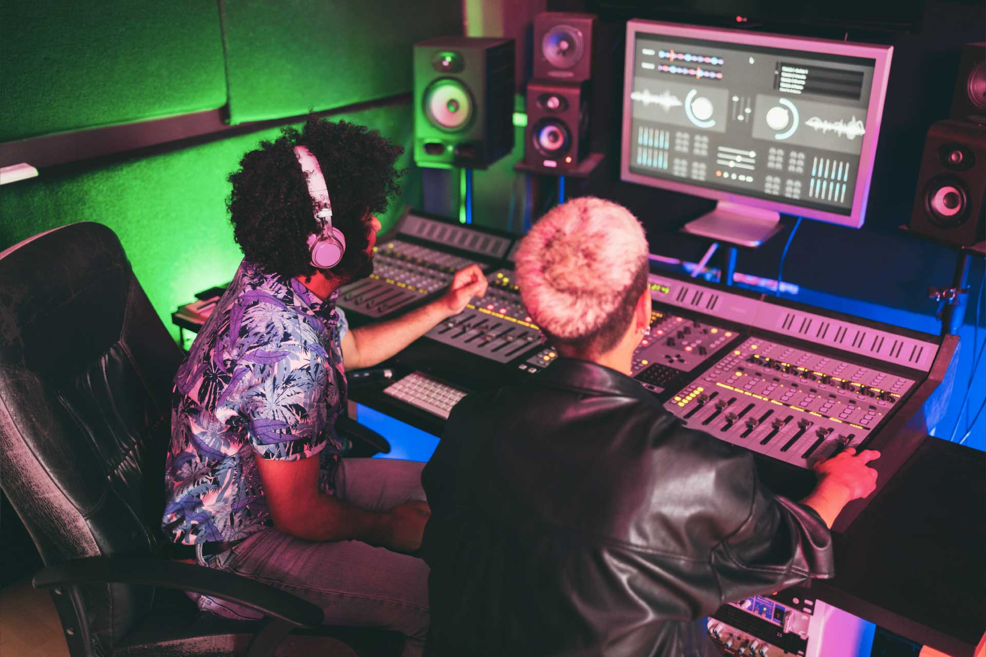 Two young music producers work at a mixing desk.