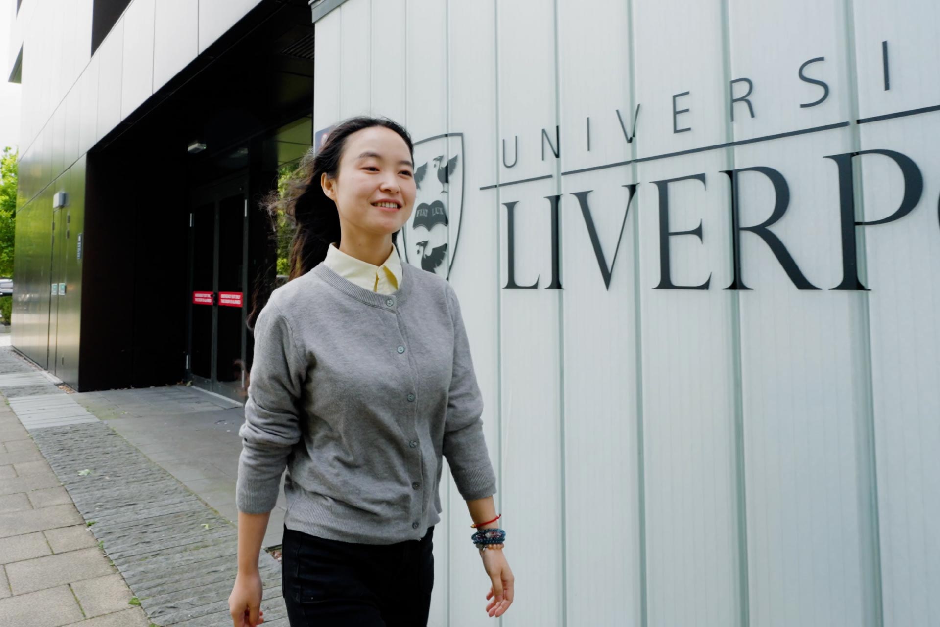 Lin Luo walking in front of University of Liverpool Management School.