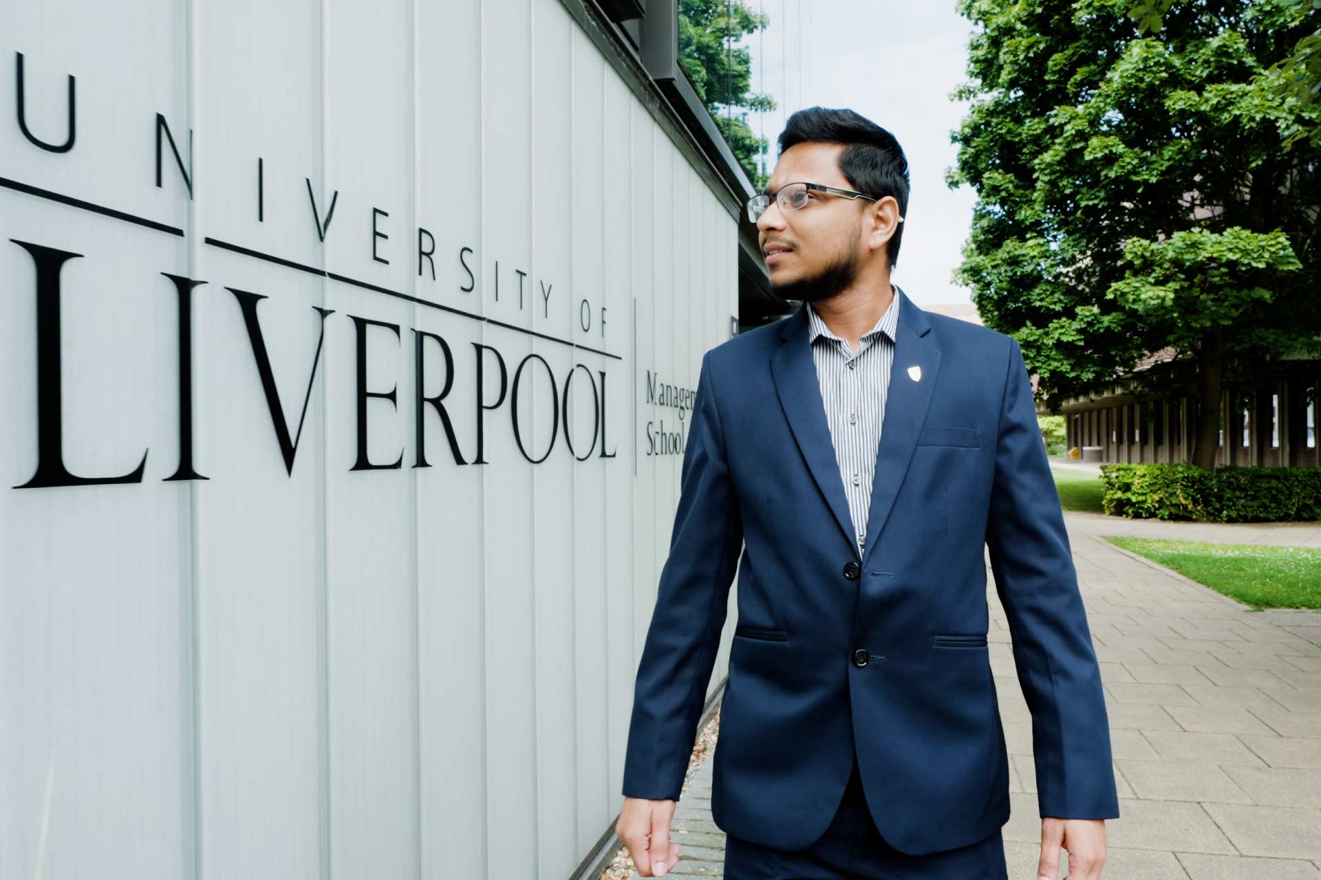 Shahid Hossain walking in front of University of Liverpool Management School.