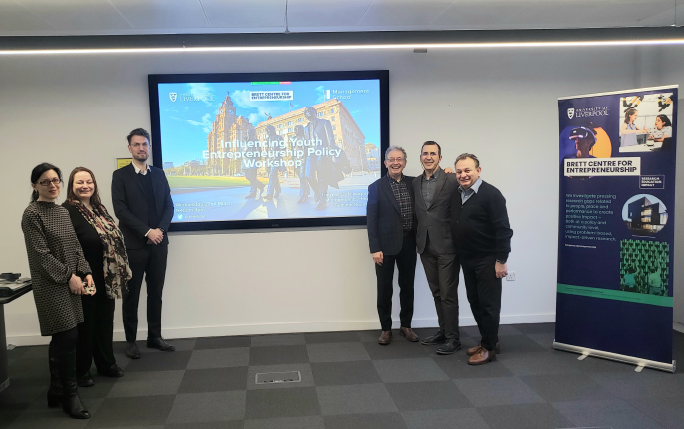 Six people taking a picture in front of projector