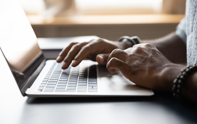 Hands typing on laptop