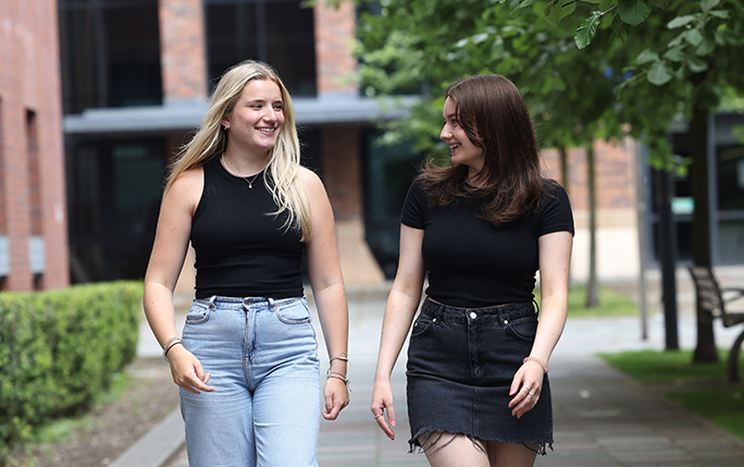 Marketing student walking on campus talking to friend