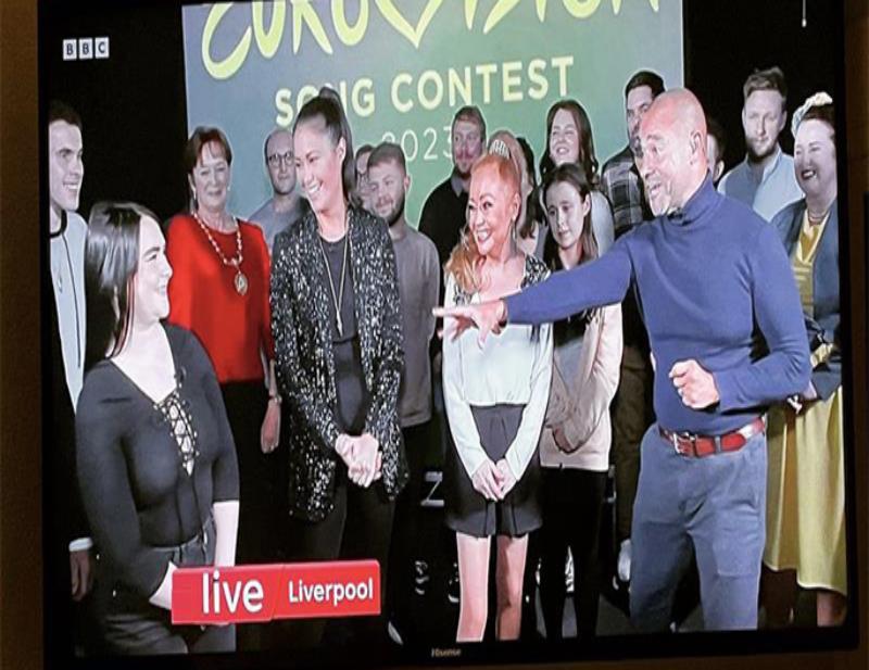 A young woman is interviewed in front of a small TV audience by three presenters, two female and one male host