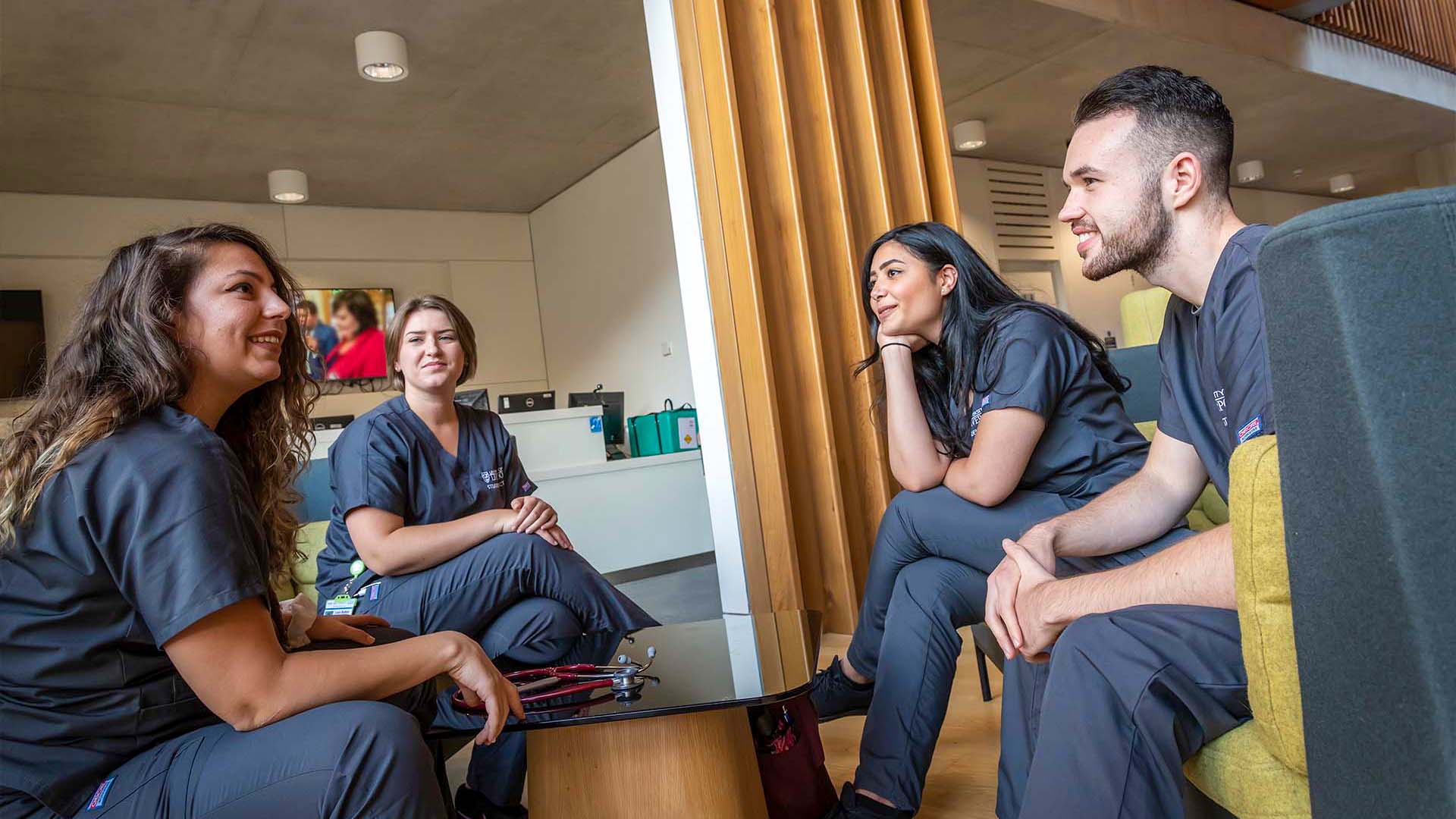 A group of students talking excitedly in a clinical setting