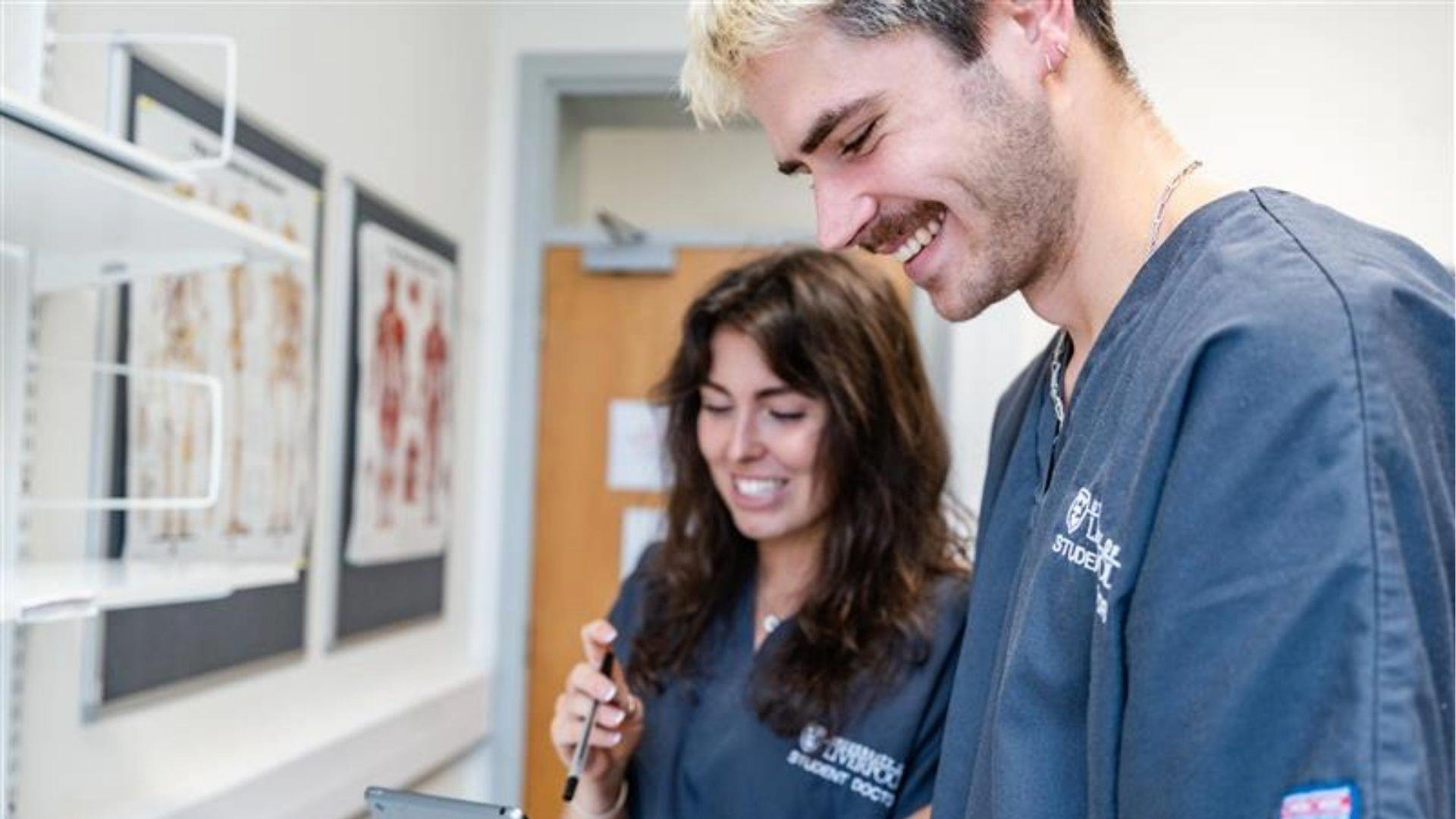 student doctors in grey scrubs in the anatomy room