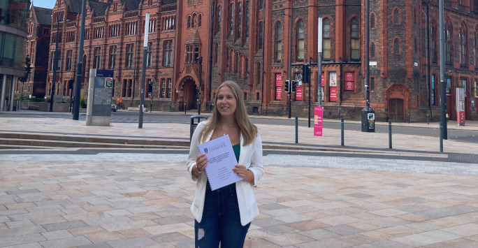 Janie Bamforth holding her dissertation at University Square