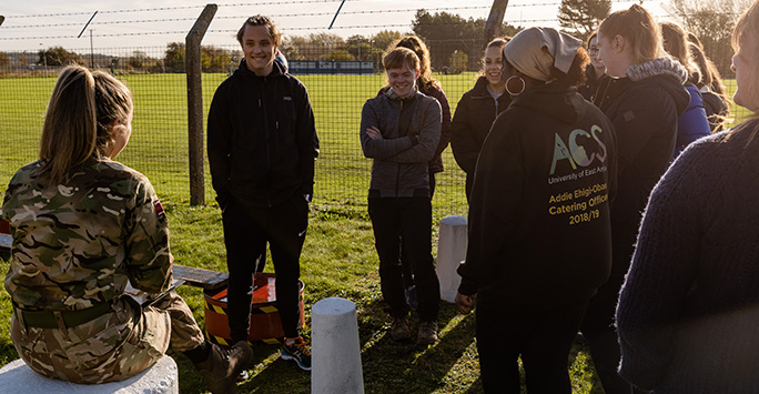 Student Doctor Andrej Krystowski stands with his colleagues listening to a debrief from an Army Instructor