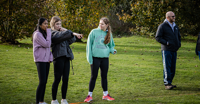 3 female students stood in a line assessing a task