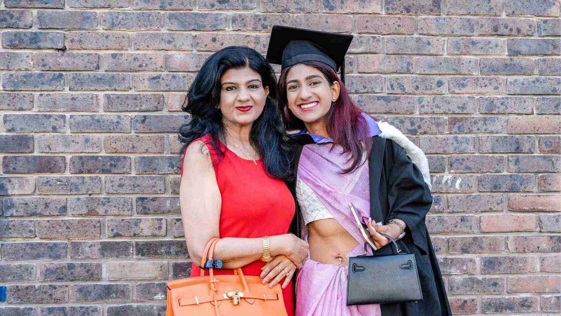 Graduate, Meera Shankar in a purple sari and gown smiles with her mum