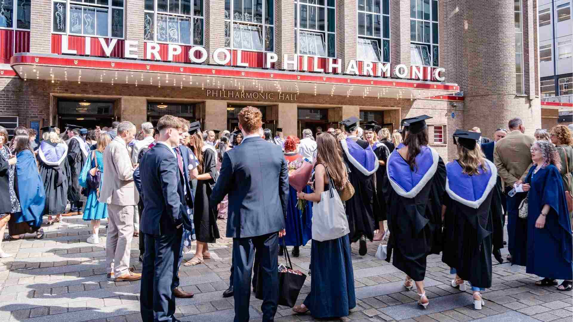 Graduates and guests gathered outside Liverpool Philharmonic Hall in academic dress, celebrating after the ceremony.