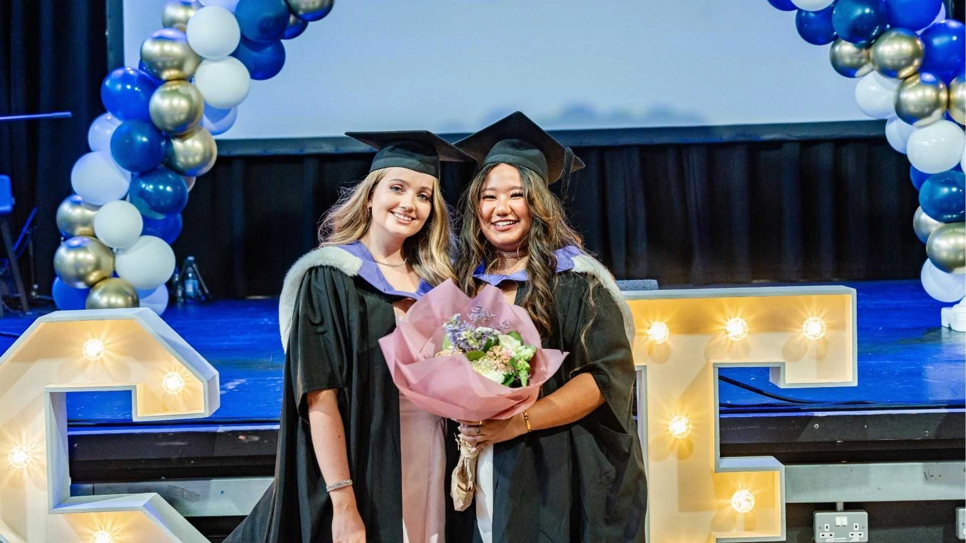 Karina Gurung and fellow graduate standing together, smiling