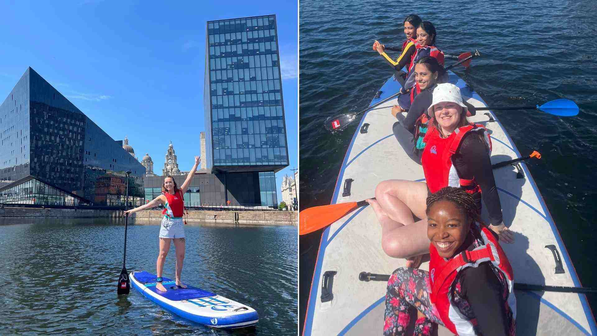Student standing on a paddleboard at the Liverpool docks with city landmarks behind and a group of 5 students sitting on one paddleboard and smiling at the camera.