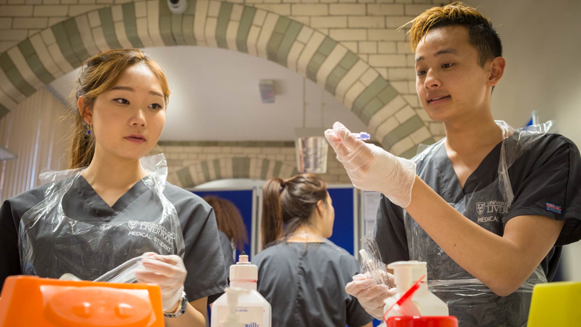 Student doctors in grey scrubs practice their clinical skills in interactive learning zone