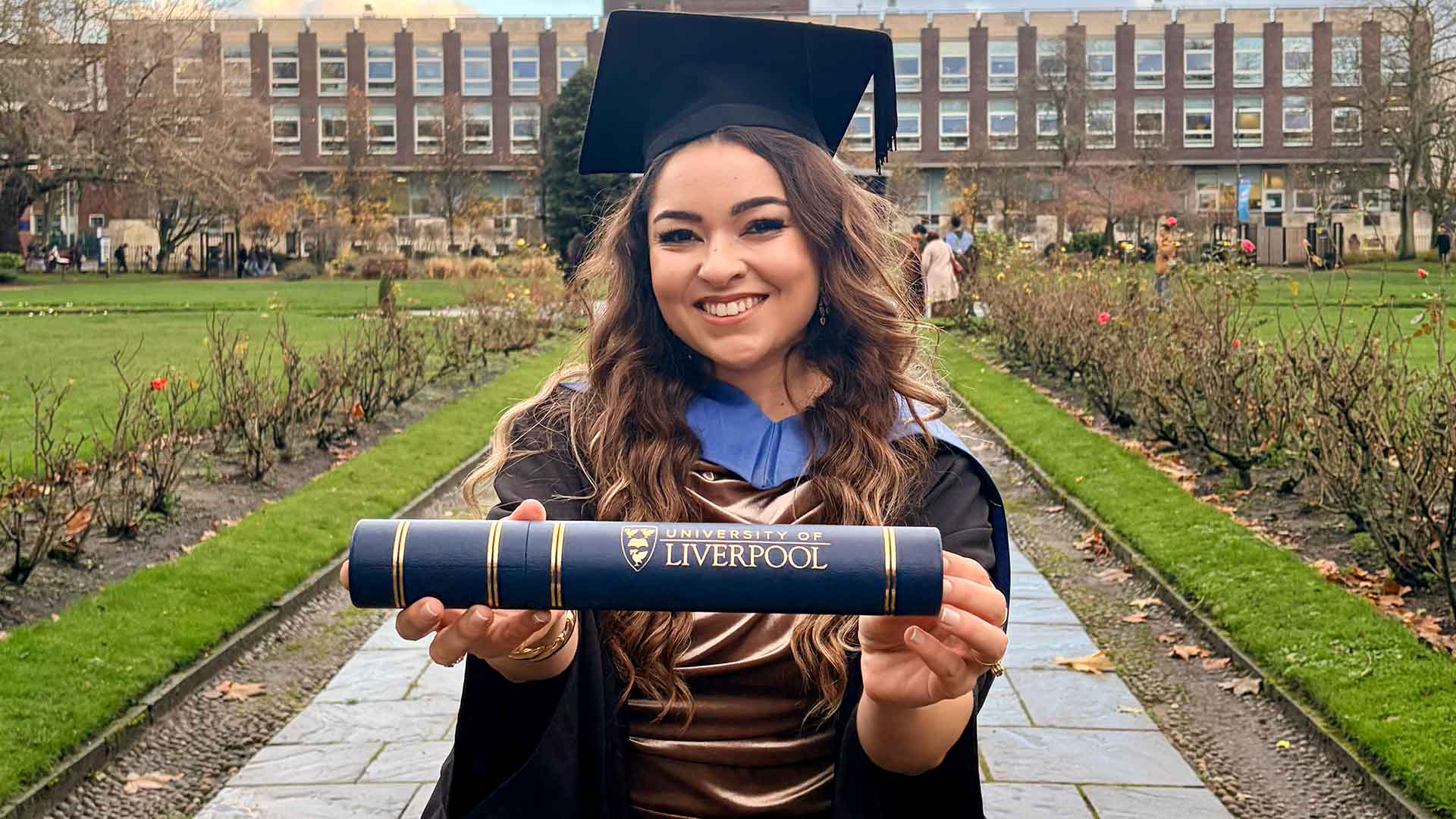 Graduate in cap and gown with degree scroll