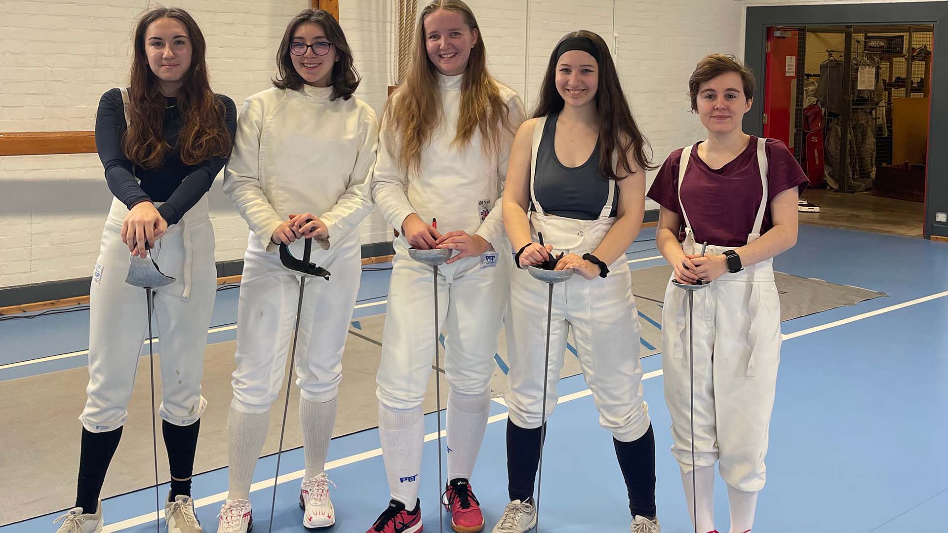 a group of students in fencing gear in a sports hall