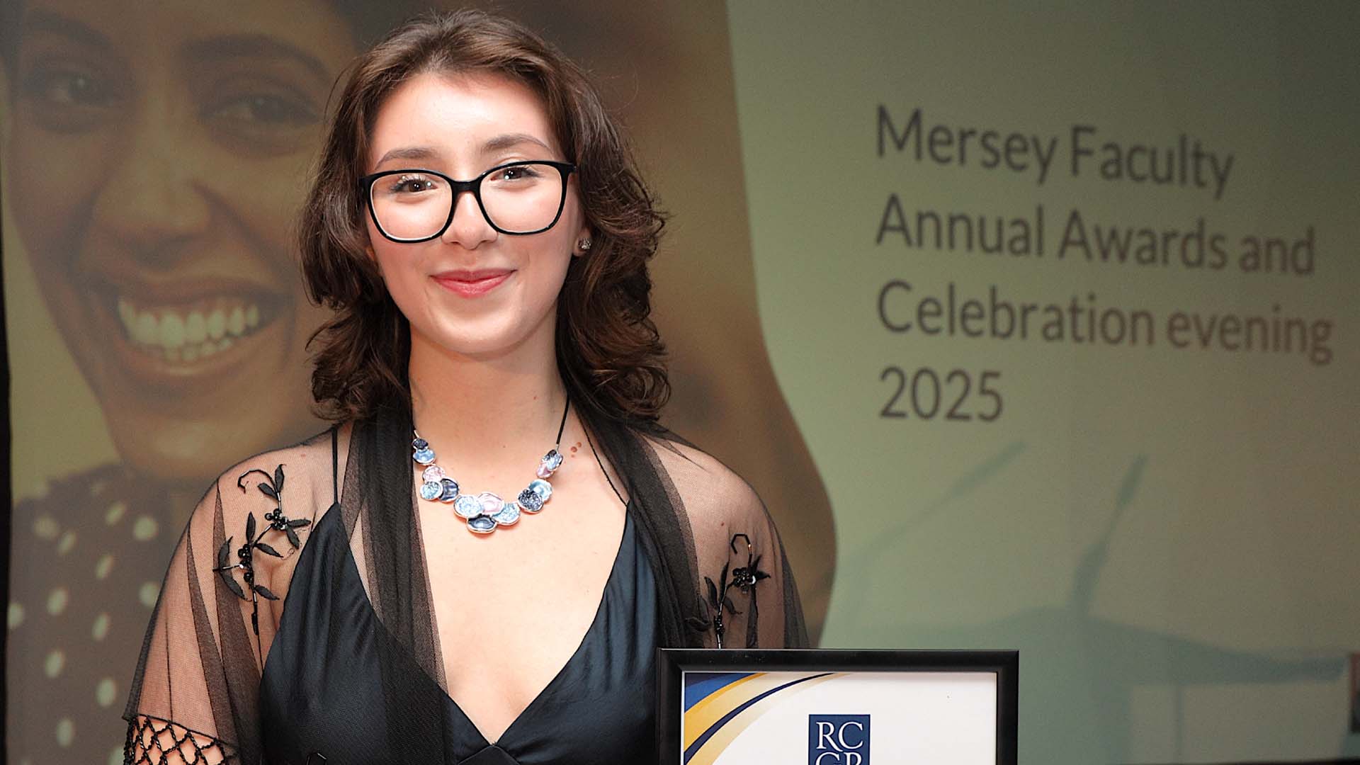 student in formalwear with a certificate at a general practice awards ceremony