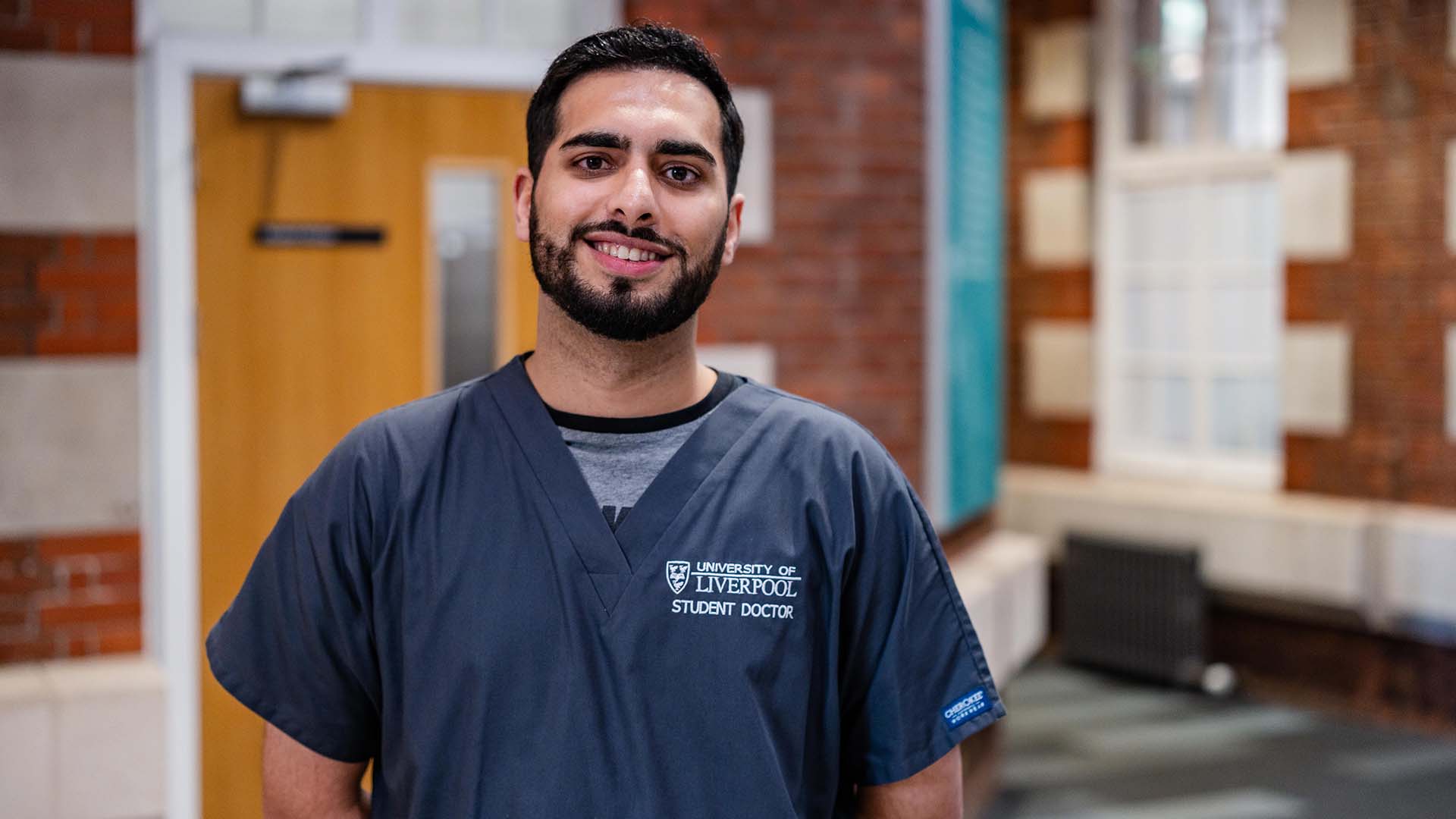 Medical student in grey scrubs in the student hub at Liverpool School of Medicine
