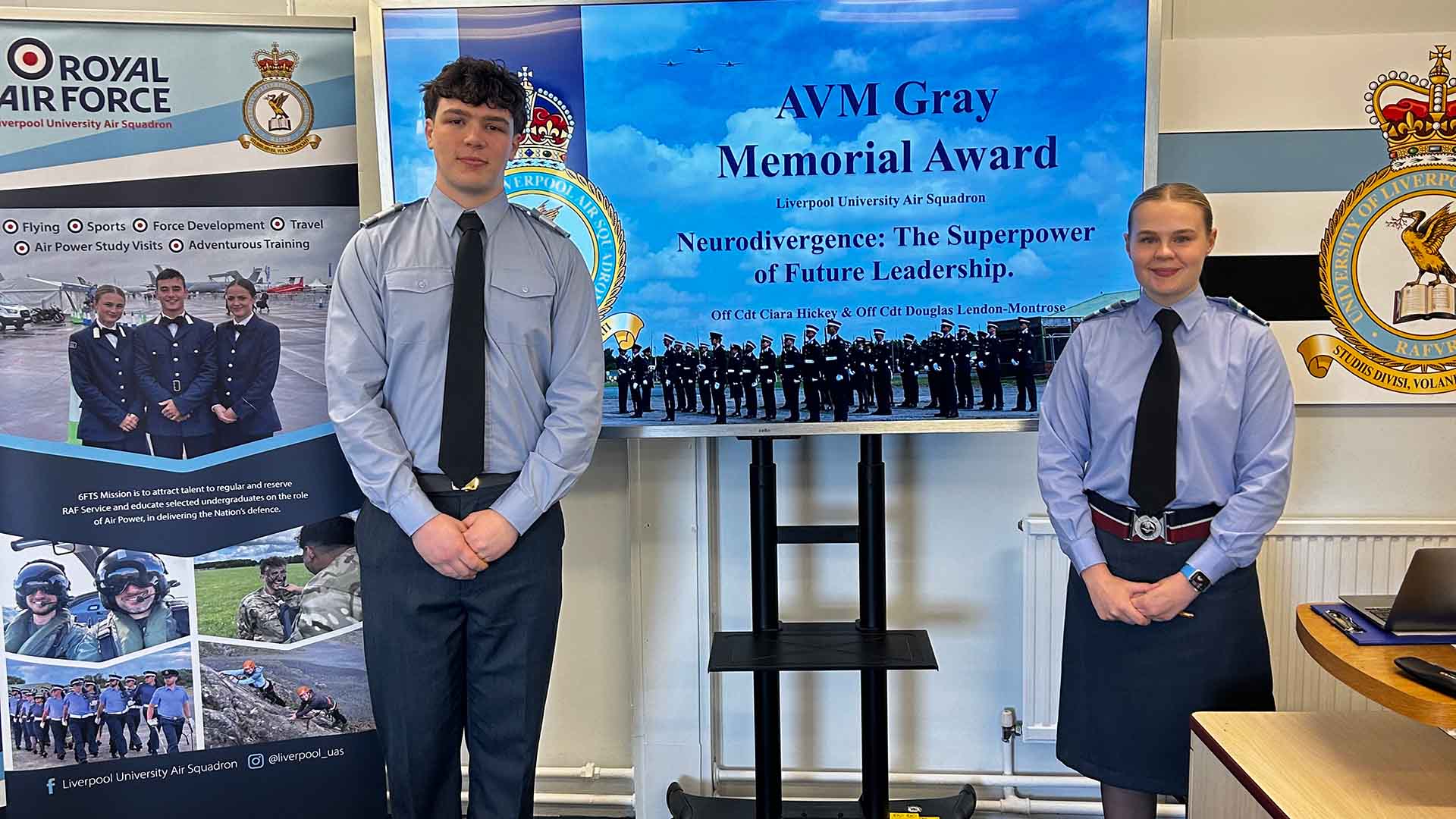 Two medical cadets in front of a sign for an RAF memorial award