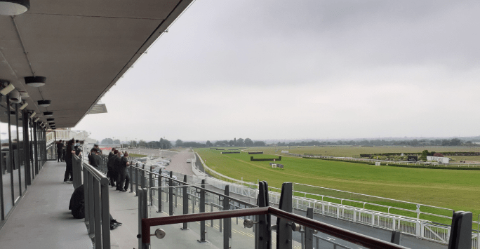 students chat on a viewing platform overlooking a race track