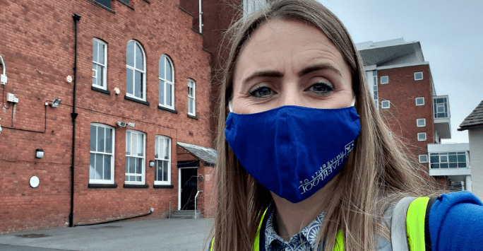 close up of a woman wearing a school of medicine branded face mask and high visibility vest