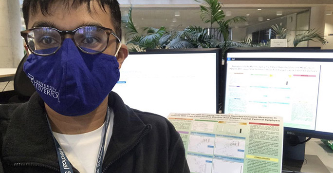 Student wearing a mask in front of computer screens