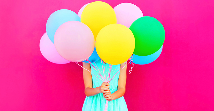 girl holding balloons that cover her face