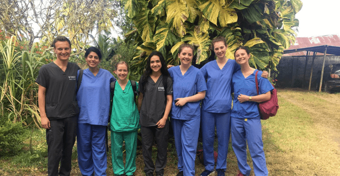 Group of medics in scrubs standing outside in greenery