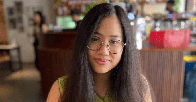 Student wearing glasses smiling to camera