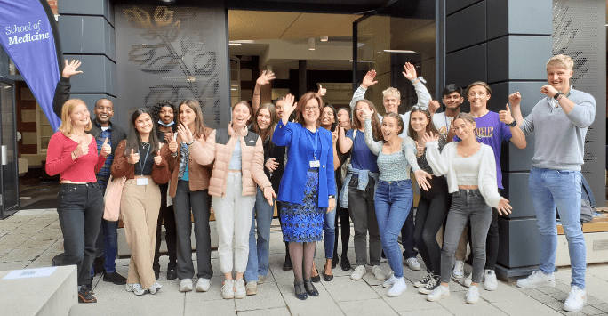 group of students with hands in the air pose with professor
