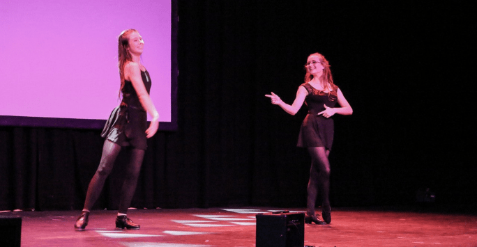 two performers on stage in black outfits