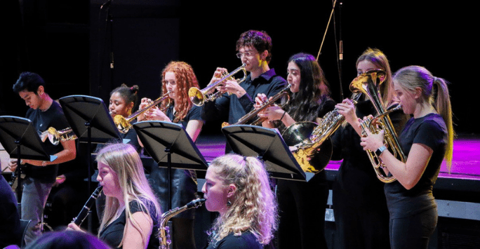 an orchestra plays trumpets and saxophones