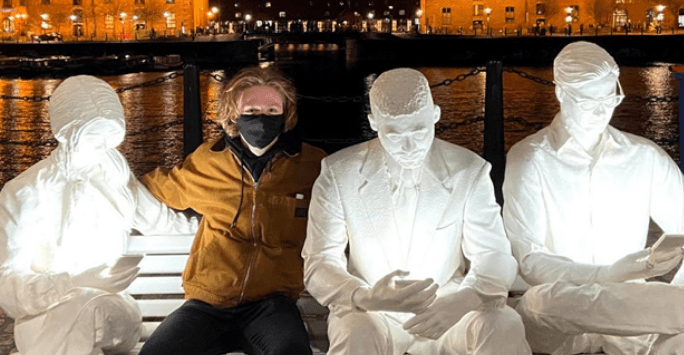man wearing a facemask poses at a light installation at Liverpool docks
