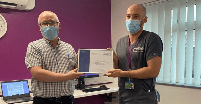 a doctor presents a certificate to a student doctor