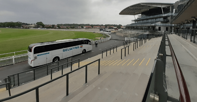 a coach arrives at a racecourse parking area