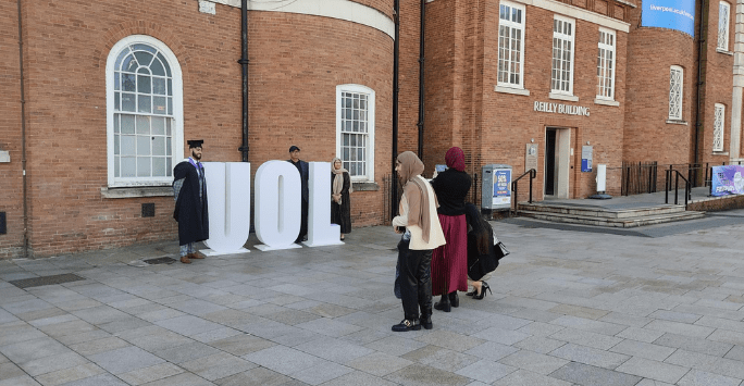 graduates pose for photos with the UOL letters