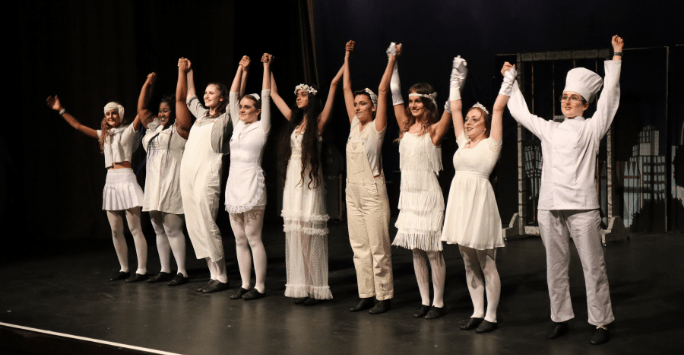 performers hold hands to take a bow on stage