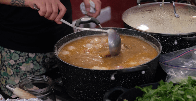a big bowl of soup that someone is stirring with a ladle
